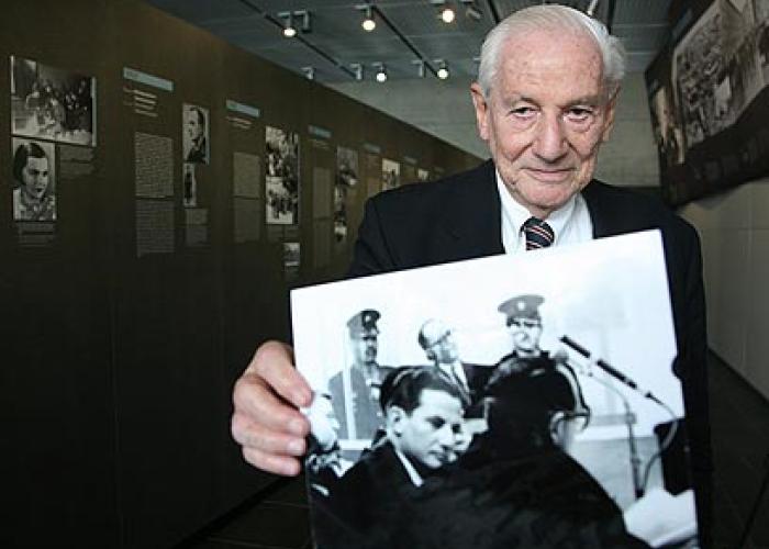 Portrait|Judge Gabriel Bach holding up a picture of himself with Eichmann in the background during the Trial|Peace Palace Library